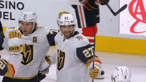 a hockey player with the number 27 on his jersey stands next to another player