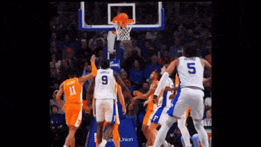 a group of basketball players are playing a game of basketball and one of them is wearing a number 5 jersey .