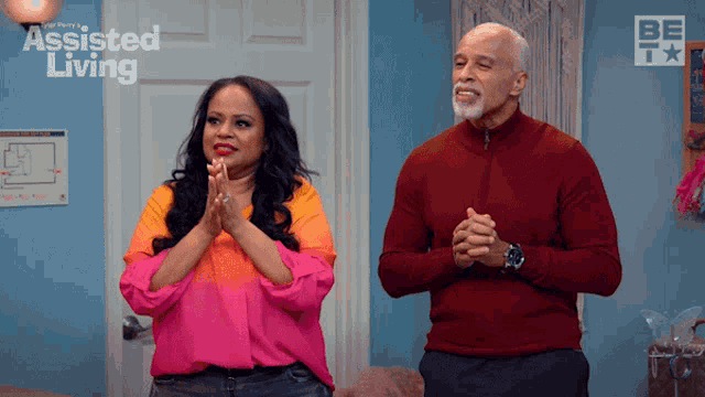 a man and a woman are clapping in front of a door that says assisted living on it