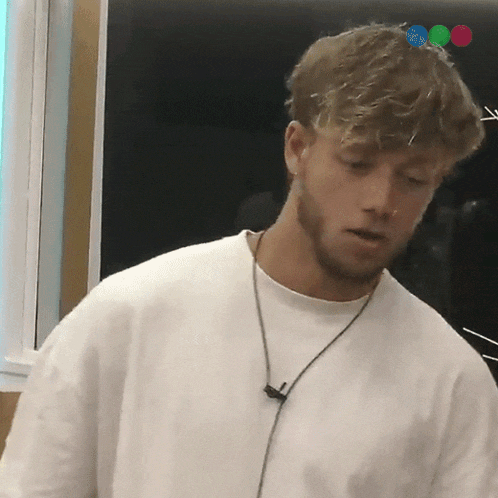 a man with a beard wearing a white t-shirt and a necklace