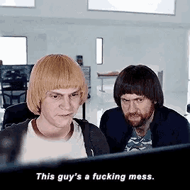 two men are looking at a computer screen and one of them says `` this guy 's a fucking mess '' .