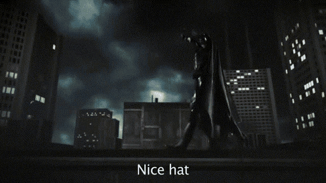 a man in a cape stands in front of a city skyline with the words " nice hat " above him