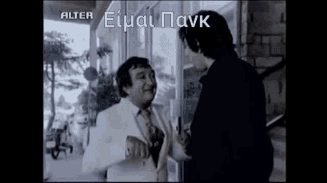 a man in a white suit and tie is talking to another man