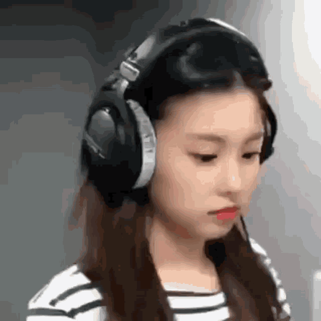 a girl wearing headphones is looking down at something .