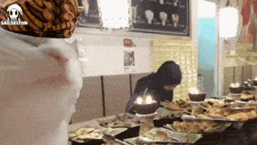 a woman in a hijab sits at a table with plates of food and candles .