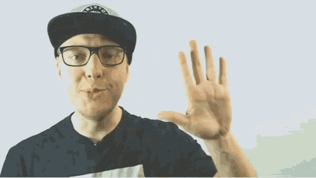 a man wearing glasses and a hat is being hit by a hand .