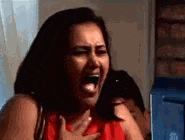 a woman is screaming on a phone while holding her chest .