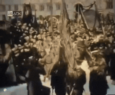 a crowd of people are gathered in front of a building with the number 24 aok on the bottom