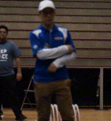 a man in a blue shirt with the word soccer on it stands in a gym
