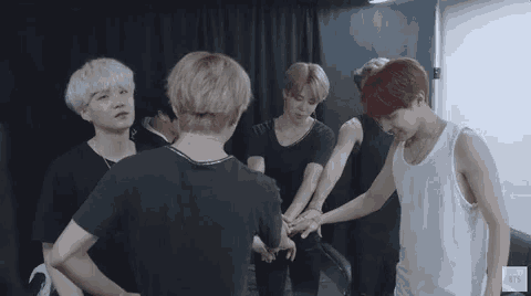 a group of young men are standing in a circle with their hands together and the word bts is on the bottom right