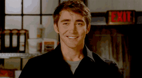 a man in a black shirt smiles in front of an exit sign