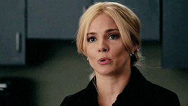 a woman with blonde hair is wearing a black jacket and earrings