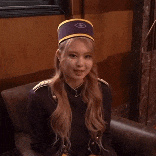 a woman wearing a purple hat and a military uniform is sitting in a chair