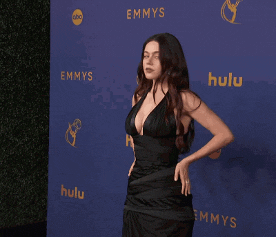 a woman in a black dress is standing in front of an emmys and hulu sign