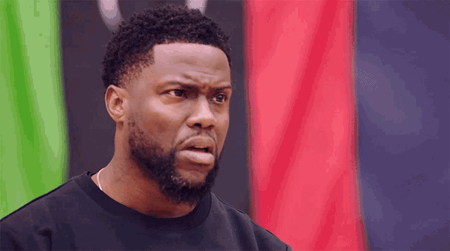 a man with a beard is wearing a black shirt and looking at the camera
