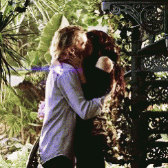 a man and a woman kissing in front of a staircase