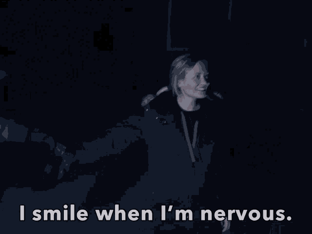 a woman in a black jacket smiles in the dark with the words " i smile when i 'm nervous " below her