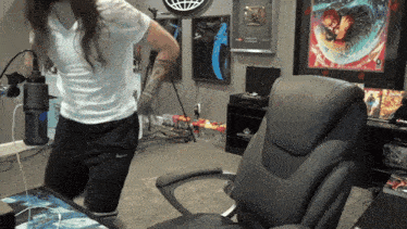 a woman in a white shirt is standing in front of a chair