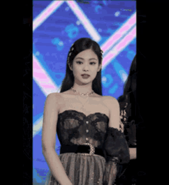 a woman in a black dress is standing in front of a stage .
