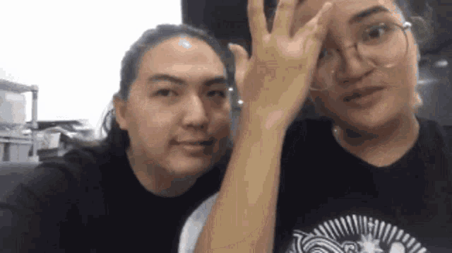 a man and a woman are posing for a picture and the man is giving the ok sign
