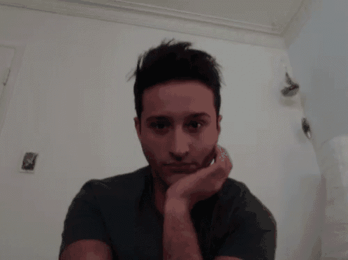 a man with a hand on his chin looks at the camera