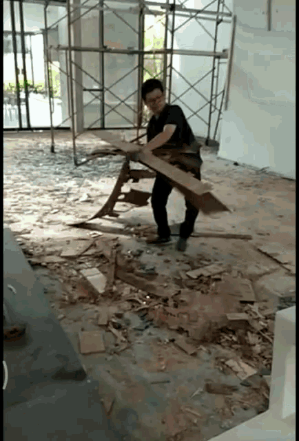 a man in a black shirt is holding a piece of wood in his hands