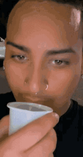 a man with a tear coming out of his nose is drinking from a white cup