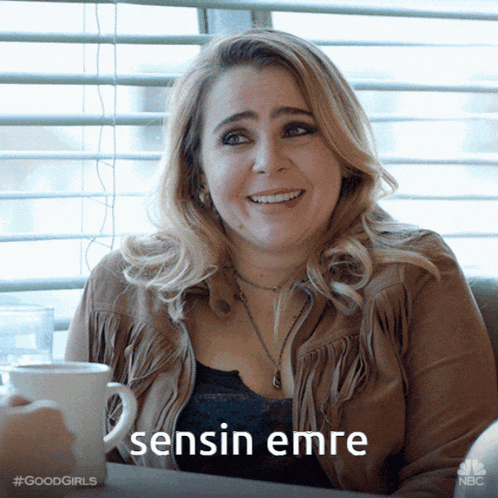 a woman sitting at a table with a cup of coffee and a caption that says " sensin emre " on it