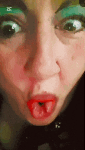 a close up of a woman 's face with red lips and green eyeshadow .
