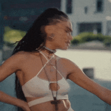 a woman in a white crop top with a cross necklace