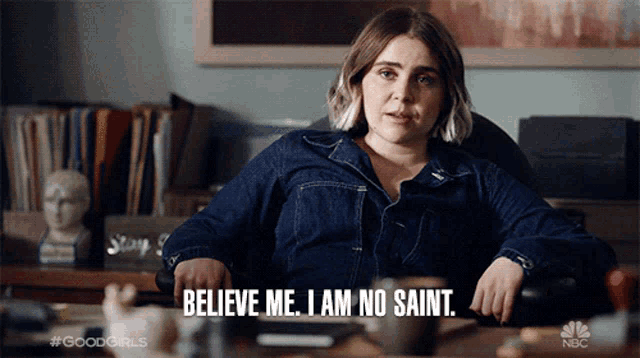 a woman sitting at a desk with the words believe me i am no saint
