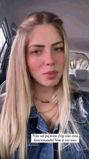 a woman is sitting in the back seat of a car wearing a denim shirt and a necklace .