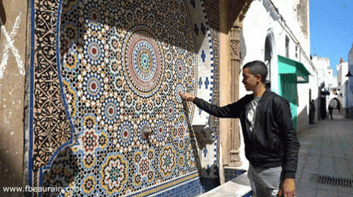a man is pointing at a colorful wall with the website www.fbeaurain.com visible in the corner