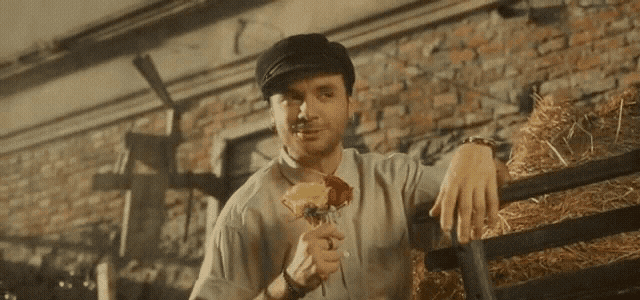 a man in a hat holds a rose in his hand