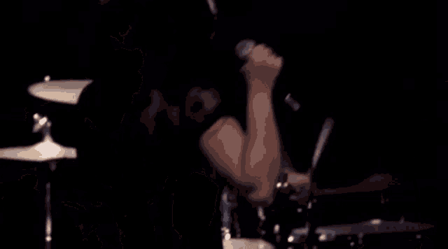 a woman is singing into a microphone while a man plays drums behind her .