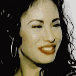 a close up of a woman 's face with a smile on her face and hoop earrings .