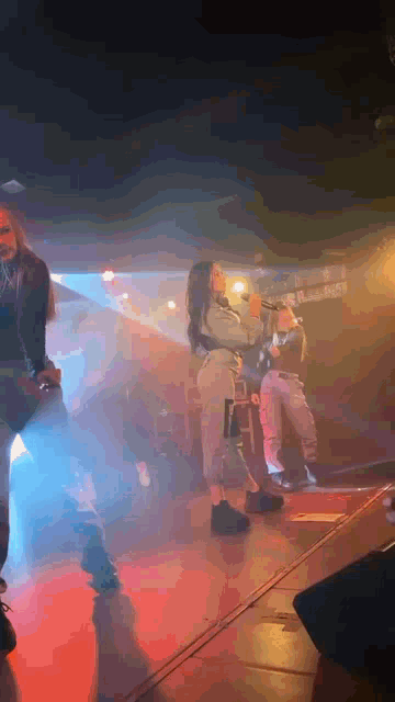 a woman is singing into a microphone on a stage in front of a crowd