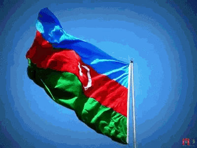 a blue red and green flag is flying in the wind