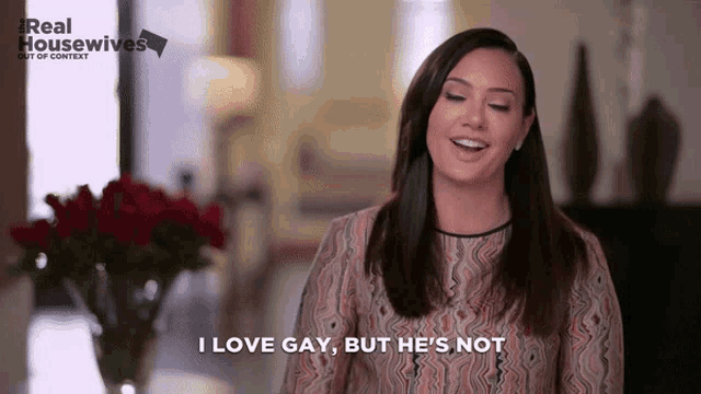 a woman says " i love gay but he 's not " in front of a vase of flowers