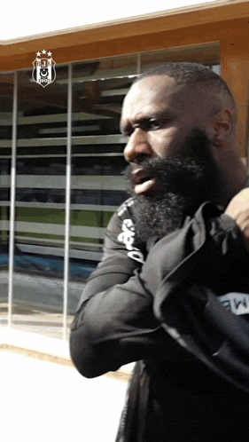 a man with a beard is standing in front of a building with a logo that says ' juventus ' on it