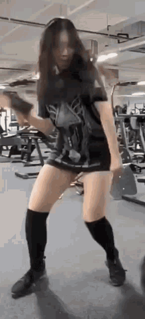 a woman is standing in a gym holding a hammer .