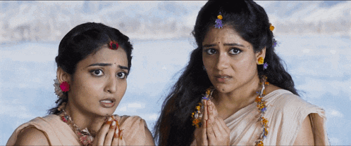 two women are standing next to each other with their hands folded in front of their faces