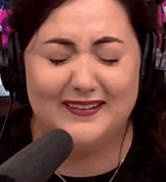 a woman wearing headphones is talking into a microphone and smiling .
