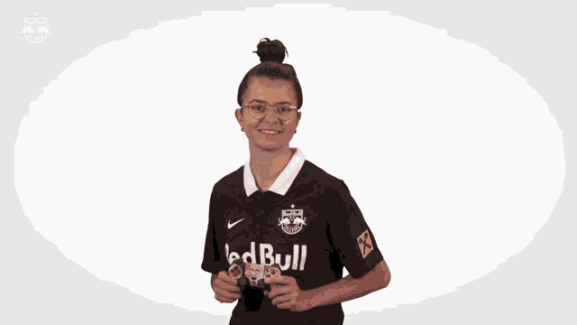 a woman in a red bull shirt holds a video game controller