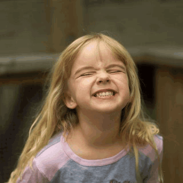 a little girl with blonde hair is making a funny face