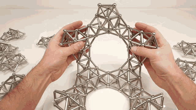 a person is holding a metal structure in their hand