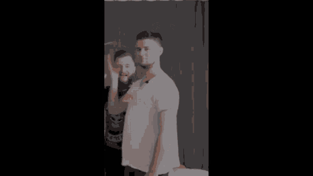 a man in a white shirt is standing next to another man in a black shirt with the word justice on it .