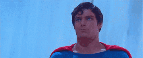 a man in a superman costume is talking on a cell phone with the words nos vemos in the background