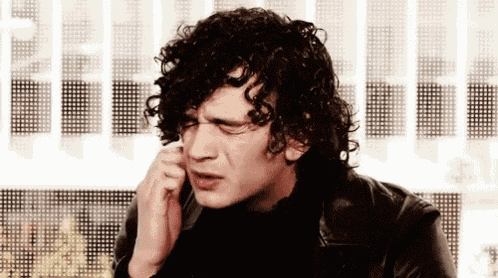 a man with curly hair is talking on a phone