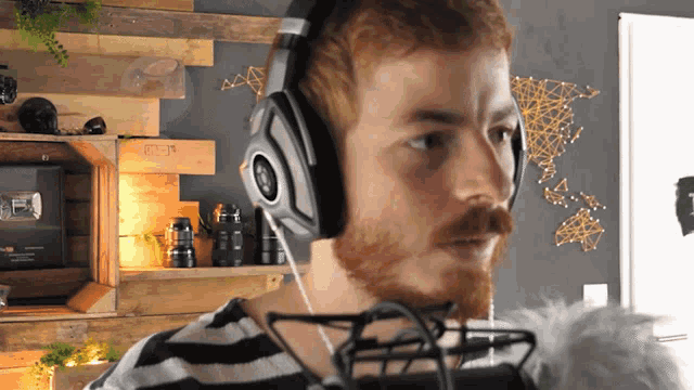 a man wearing headphones and a microphone with the letter t on his shirt